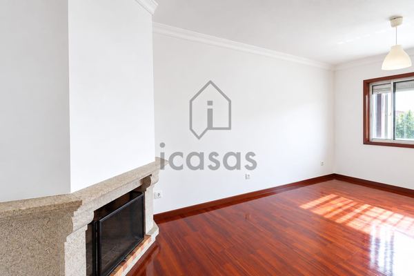 Sala com lareira e janela com luz natural sobre o soalho de madeira